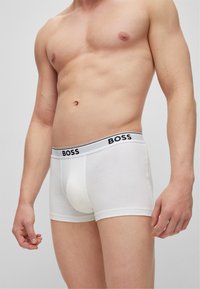 Boxer shorts blancs en coton, avec une ceinture de marque noire et blanche. Design ajusté avec une texture lisse.