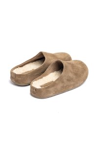 Zapatillas de ante marrón con un suave forro crema, punta redondeada, diseño tipo slip-on y un estilo minimalista. Sin herrajes ni acentos visibles.