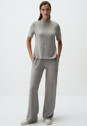 Lichtgrijze top met korte mouwen en hoge hals, gecombineerd met wijde grijze broek. Zachte textuur, casual pasvorm en subtiele naaddetails.