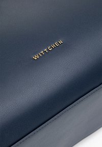 Granatowa skórzana torba o teksturowanej powierzchni, z złotym logo "WITTCHEN" i starannym przeszyciem na krawędziach.