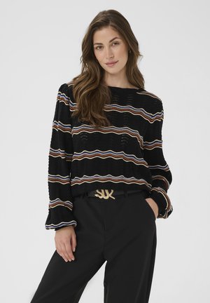 Black knit sweater featuring multicolored horizontal stripes, long sleeves, and a loose fit, paired with high-waisted black trousers and a decorative belt.