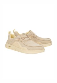 Scarpe beige slip-on con tomaia in tessuto testurizzato e interno imbottito. Presentano una punta rotonda, dettagli in pizzo e una suola imbottita con fori d'aria.