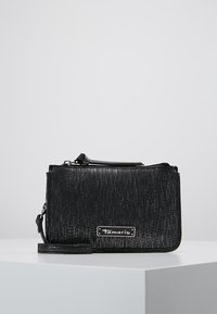 Svart texturerad axelväska med dragkedjestängning, utrustad med en silverfärgad logoplåt, avtagbar rem och rektangulär form.