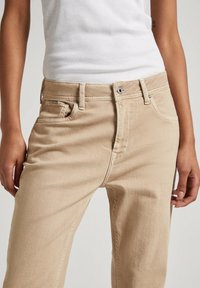 Beige džíny z denimu se rovnými nohavicemi, s knoflíkovým zapínáním, poutky na opasek a nenápadnými švy na kapsách.