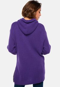 Lila Kapuzenpullover mit strukturierter Strickware, langen Ärmeln und einer Kängurutasche. Verfügt über seitliche Reißverschlüsse und eine lockere Passform für zusätzlichen Komfort.