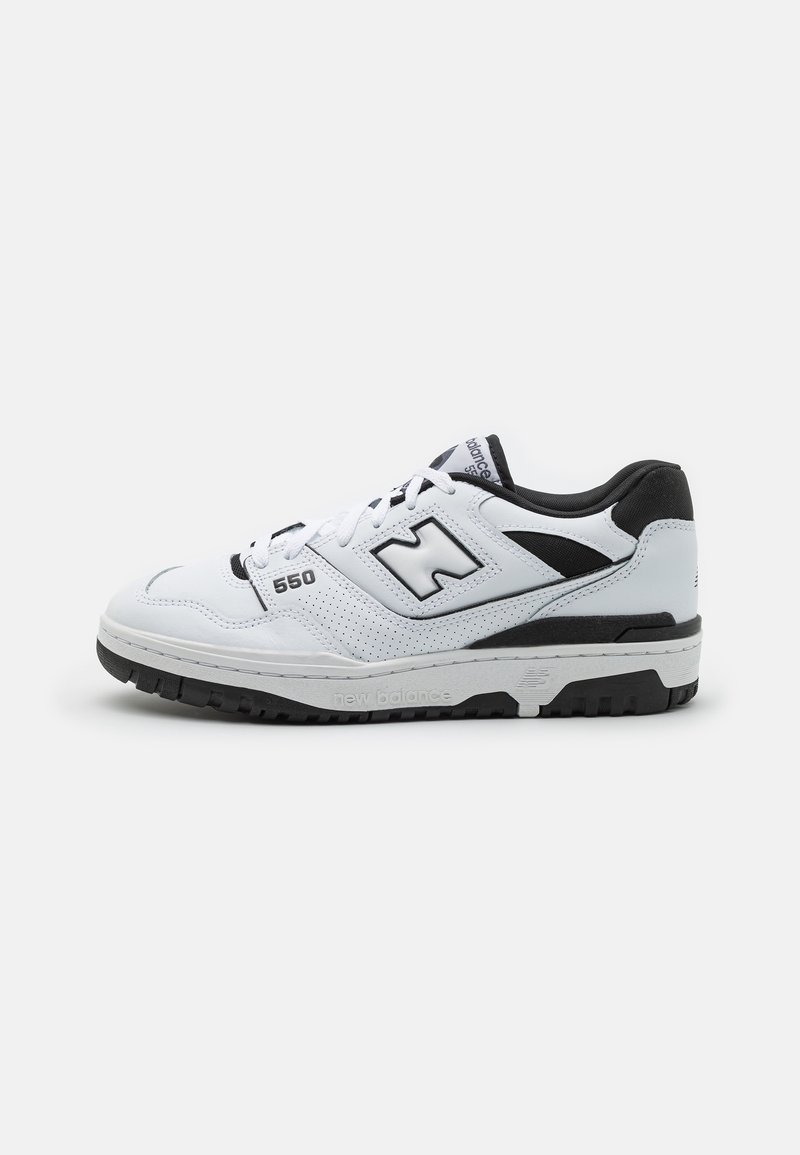 Valkoiset ja mustat New Balance 550 -tennarit, joissa on rei'itetty sivupaneeli, "N"-logo ja musta pohja, tasaisella harmaalla taustalla.