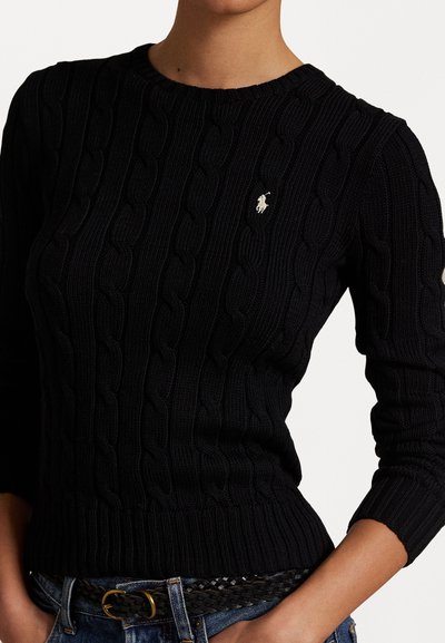 Black knitted sweater featuring cable knit design, round neckline, and three-quarter sleeves. Small white embroidered logo on chest.