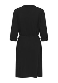 Rochie neagră cu guler, mâneci trei sferturi suflecate, talie cu curea și croială lejeră. Material neted cu un design simplu.