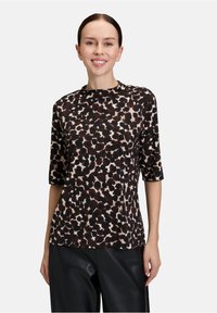 Brązowa i beżowa bluzka w panterkę, krótki rękaw, okrągły dekolt, miękki materiał, luźny krój, zestawiona z czarnymi skórzanymi spodniami.