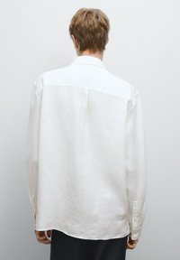 Witte linnen shirt met een relaxte pasvorm, lange mouwen, een achterste yoke-naad en knoopmanchetten. Gladde textuur en casual ontwerp.
