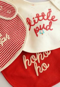Set aus drei Lätzchen mit einem rot-weißen Streifenmuster, einem cremefarbenen Lätzchen mit aufgedrucktem Text und einem roten Lätzchen mit kontrastierenden Schriftzügen.