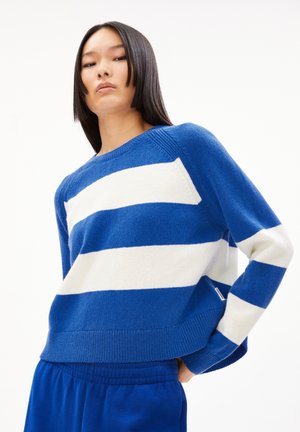 Pull rayé bleu et blanc en tissu tricoté doux, présentant un col ras du cou classique et des poignets et un ourlet côtelés. Détails incluant des étiquettes sur les côtés.