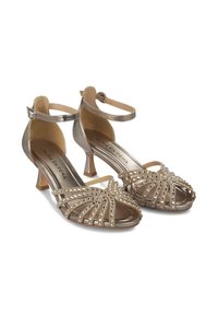 Las sandalias de tacón alto de bronce metálico cuentan con brillantes rhinestones, un diseño de punta abierta y correas para el tobillo con cierre de hebilla.