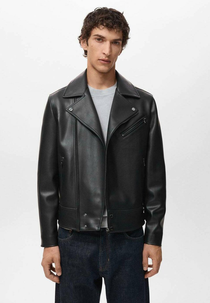 La veste de moto en cuir noir se distingue par un large col, des poches zippées et une silhouette ajustée. Sa texture lisse présente un minimum de détails.