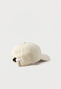 Beige cotton baseball cap with a curved brim, adjustable back strap, and soft texture. Features ventilation holes and a simple design.
