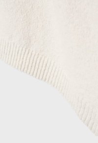 Uldblandingsstof i cremefarve med ribbet tekstur og afsluttet kant. Blød og let dunet overflade, synlig skrå kant.