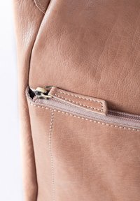 Light brown leather bag featuring a subtle grain texture, a front zip pocket with a metal zipper, and contrasting stitching detail.