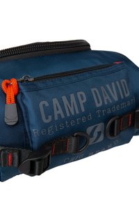 Navyblaue rechteckige Tasche aus strapazierfähigem Material, ausgestattet mit einem Reißverschluss, orangefarbenem Ziehband, gebrandetem Text und schwarzen Trägern mit roter Naht.