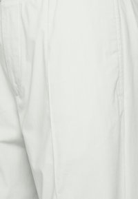 Světlé šedé kalhoty s hladkou, jemnou texturou. Mají boční kapsy a rovné nohavice, vyrobené z prodyšné bavlněné směsi. Jednoduchý design.