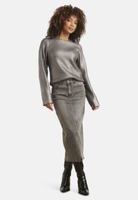 Zilverkleurige geribbelde langemouwen trui gecombineerd met een grijze spijkerrok, met een rechte snit en zijsplitten, gedragen met zwarte enkellaarsjes.