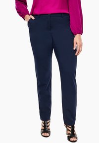Pantalon bleu marine en tissu lisse, avec une taille mi-haute, deux poches latérales et une coupe droite. Sandales à lanières élégantes complètent la tenue.