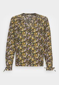 Blumenbluse in Schwarz mit gelben, lila und weißen Blumen. Lange Ärmel mit Bindebändern an den Handgelenken und einem runden Ausschnitt.