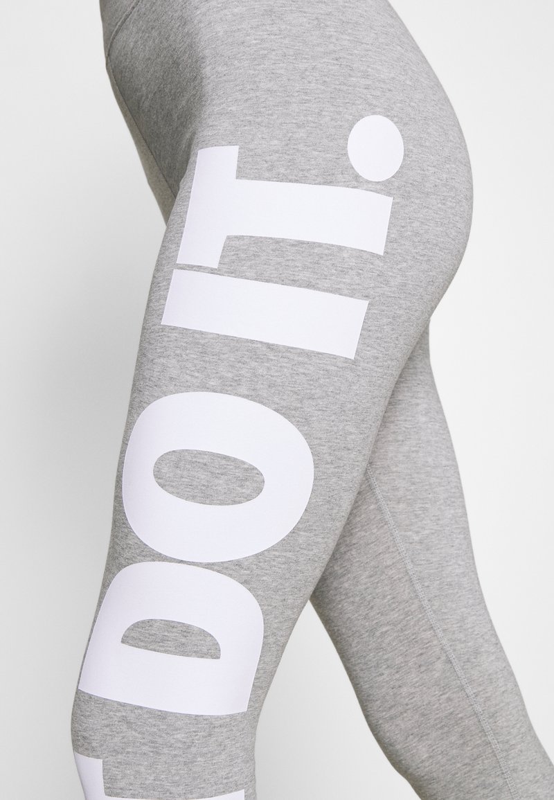 Leggings grises hechos de un material suave, con un gran texto blanco "hazlo" en el lado, con un diseño liso y ajustado, y detalles de costura mínimos.