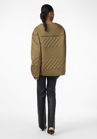 Quilted olive green jacket with a boxy shape, large sleeves, and diamond patterns, paired with black leather pants and heeled shoes.