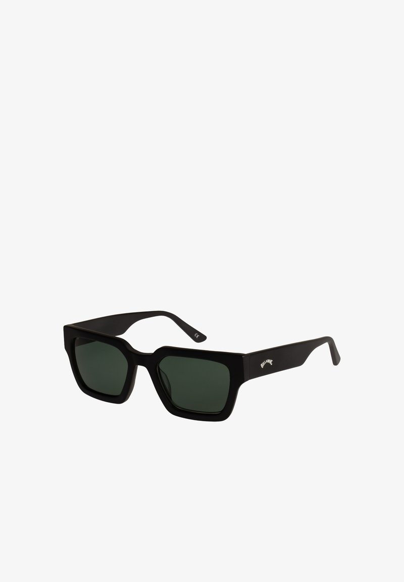 Gafas de sol rectangulares negras con montura gruesa y lentes verde oscuro, con un pequeño logo blanco en la patilla.