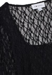 Top in pizzo nero con motivo a maglia aperta e texture. Presenta una scollatura a girocollo e un piccolo fiocco decorativo sul davanti. L'etichetta riporta "B♥ANGEL".