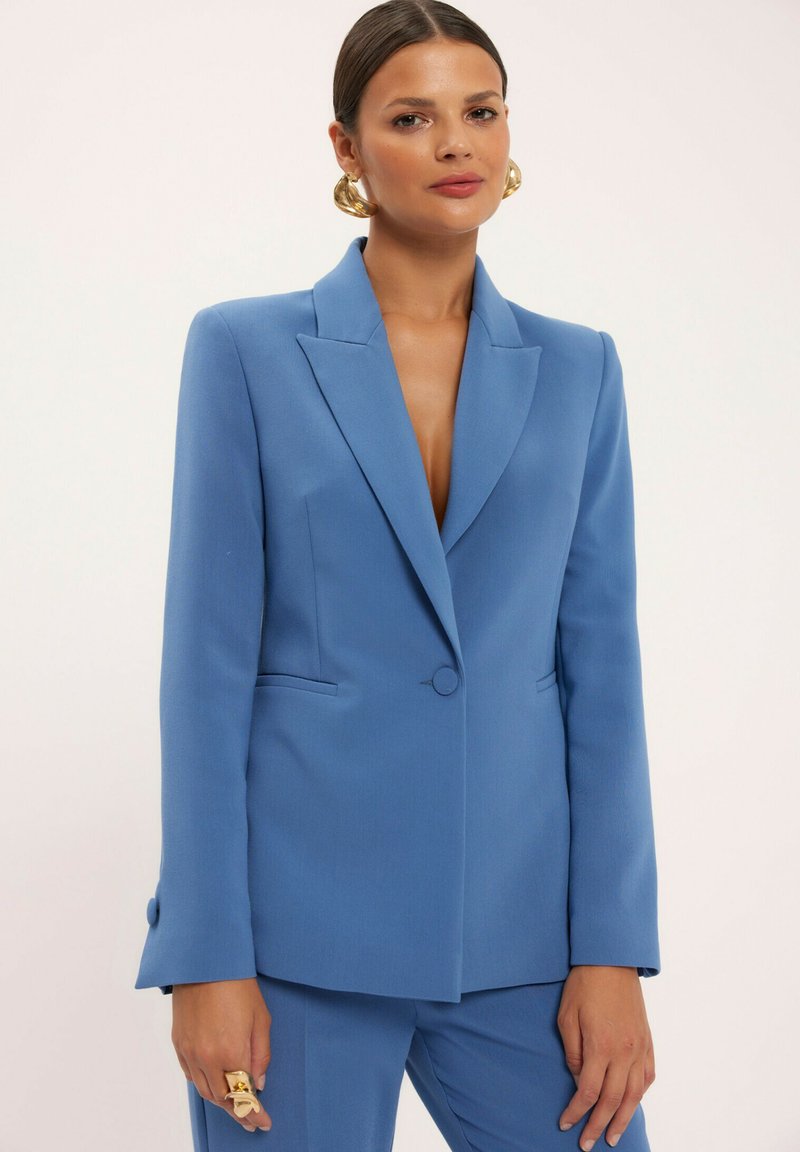 Niebieska żakiet z klapami, z pojedynczym zapięciem na guzik i kieszeniami po bokach. Wykonana z teksturowanej tkaniny, o dopasowanym kroju.