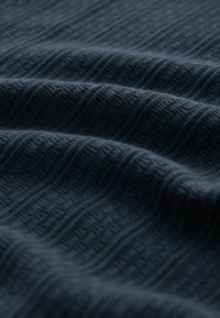 Tela azul oscuro texturizada con un patrón ondulado, que presenta finas estrías y sutiles variaciones en tonalidad y profundidad.