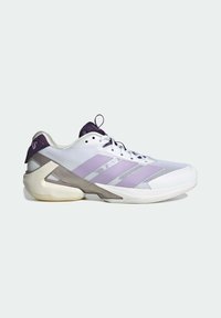 Baskets de sport blanches et violet clair avec une tige en mesh, trois bandes sur le côté, un renfort épais au talon et une languette noire avec tirette.