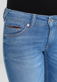Vaqueros de mezclilla azul claro con un ajuste slim. Cuenta con un cierre de botón, cinco bolsillos y detalles de costura en el bolsillo para monedas.