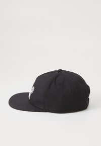 Black baseball cap with a flat brim, made of cotton. Features embroidered logo on the front, six ventilation eyelets, and adjustable strap.