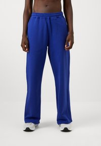 Zili kokvilnas sporta bikses ar elastīgu jostasvietu un sānu kabatām, kurām ir brīvs piegriezums un taisna kāju forma.