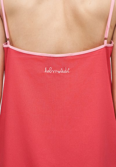 Οπίσθια όψη ενός ατόμου που φοράει κόκκινο φόρεμα χωρίς μανίκια με λεπτούς ροζ ιμάντες και λευκό κεντητό κείμενο "helmstedt" κοντά στο πάνω μέρος της πλάτης.