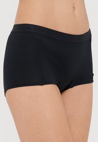 Fekete boxernadrág puha anyagból, sima derékpánttal, diszkrét márkázással és testhezálló, kényelmes fazonnal.