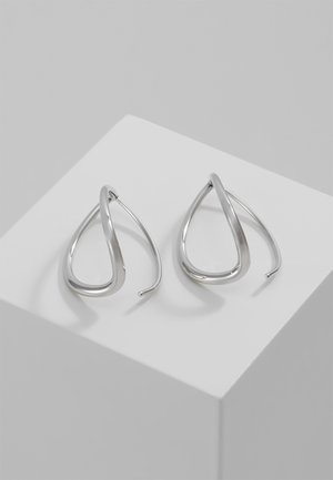 Paire de boucles d'oreilles en argent poli en forme de goutte avec un design incurvé superposé, exposée sur un piédestal blanc.