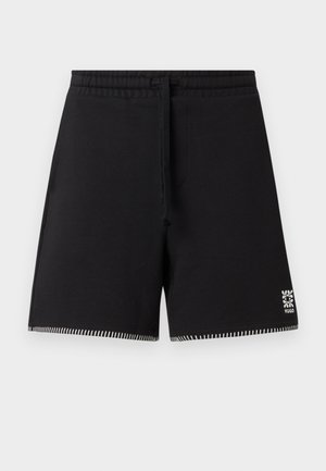 Short noir à cordon avec taille élastique, ourlet blanc cousu et petit logo floral blanc sur la partie inférieure de la jambe droite.