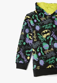 Sudadera negra con estampados coloridos al estilo graffiti de "Batman", "Pingüino" y formas abstractas. Fabricada en tela suave con dobladillo acanalado.