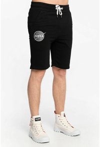 Schwarze Sweatshorts mit Seitentaschen, weißem Kordelzug und NASA-Logo am rechten Oberschenkel. Kombiniert mit weißen High-Top-Sneakern.