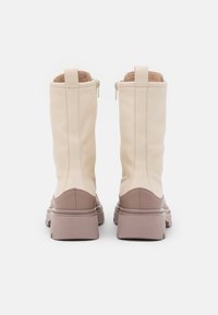 Bottes en cuir beige à la texture lisse, hauteur mi-mollet, dotées d'une semelle en caoutchouc marron clair et de fermetures éclair à l'arrière pour un accès facile.