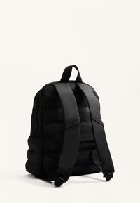 Fekete párnázott hátizsák állítható pántokkal, felső fogóval és oldalsó zsebekkel. Simaherű felület, minimalista dizájn.