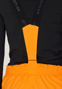 Svart långärmad topp med orange justerbara hängslen; hängslena har en enfärgad och texturerad känsla, fäster vid ett elastiskt, rynkat midjeband.