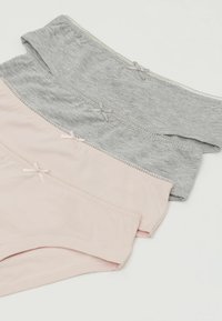 Drei Paare Damenunterwäsche aus Baumwolle in hellrosa, grau und dunkelgrau. Jedes hat ein Ribbonsverzierung und gewellte Kanten.