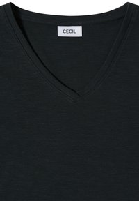 T-shirt noir à col en V avec une étiquette de marque rectangulaire blanche portant la mention "CECIL" cousue à l'intérieur du col.