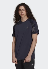 Marineblaues sportliches T-Shirt mit Rundhalsausschnitt, kurzen Ärmeln und kontrastierenden Camouflage-Muster-Akzenten an den Schultern. Kleines Logo auf der Brust.