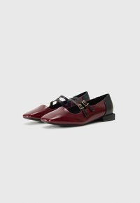 Burgundy nahka loaferit terävällä kärjellä, mustat yksityiskohdat ja kolme koristeellista nauhaa, joissa on kultaiset soljet. Matala lohkoluukku. Sileä pinta.