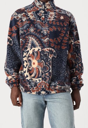 Pull-over en polaire avec une demi-fermeture éclair, aux motifs floraux et géométriques bleus, orange et crème ; coupe décontractée avec poignets et ourlet élastiqués.